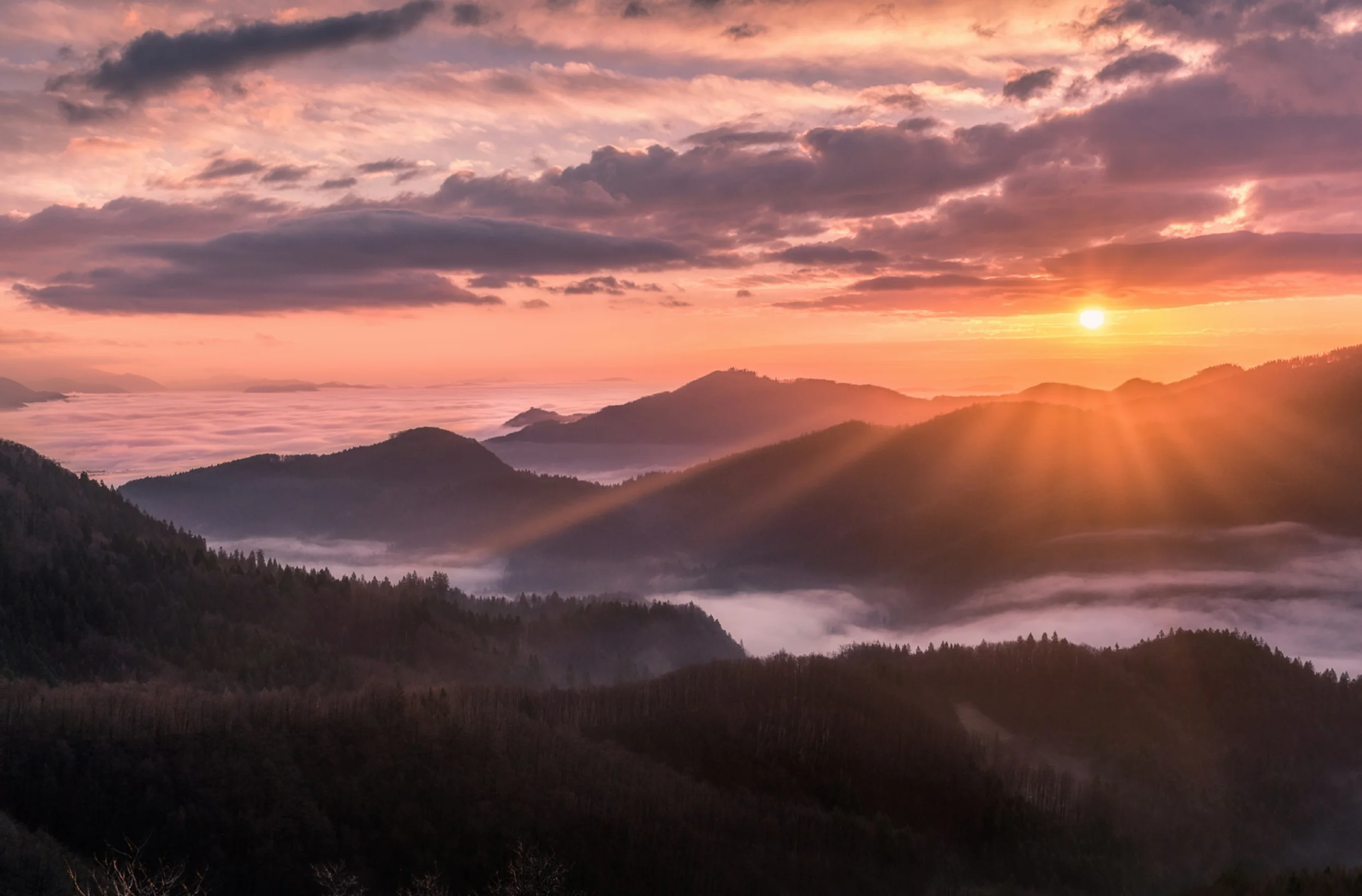 Sunrise over a distant misty and mountainous landscape.