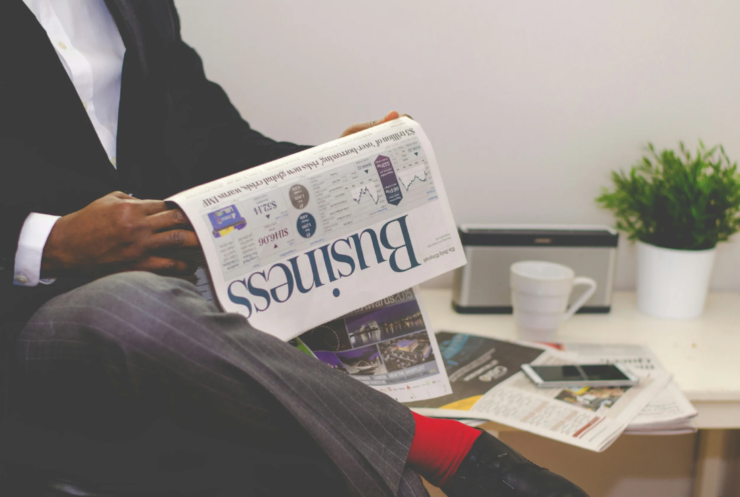 A man with red socks reading a business paper.