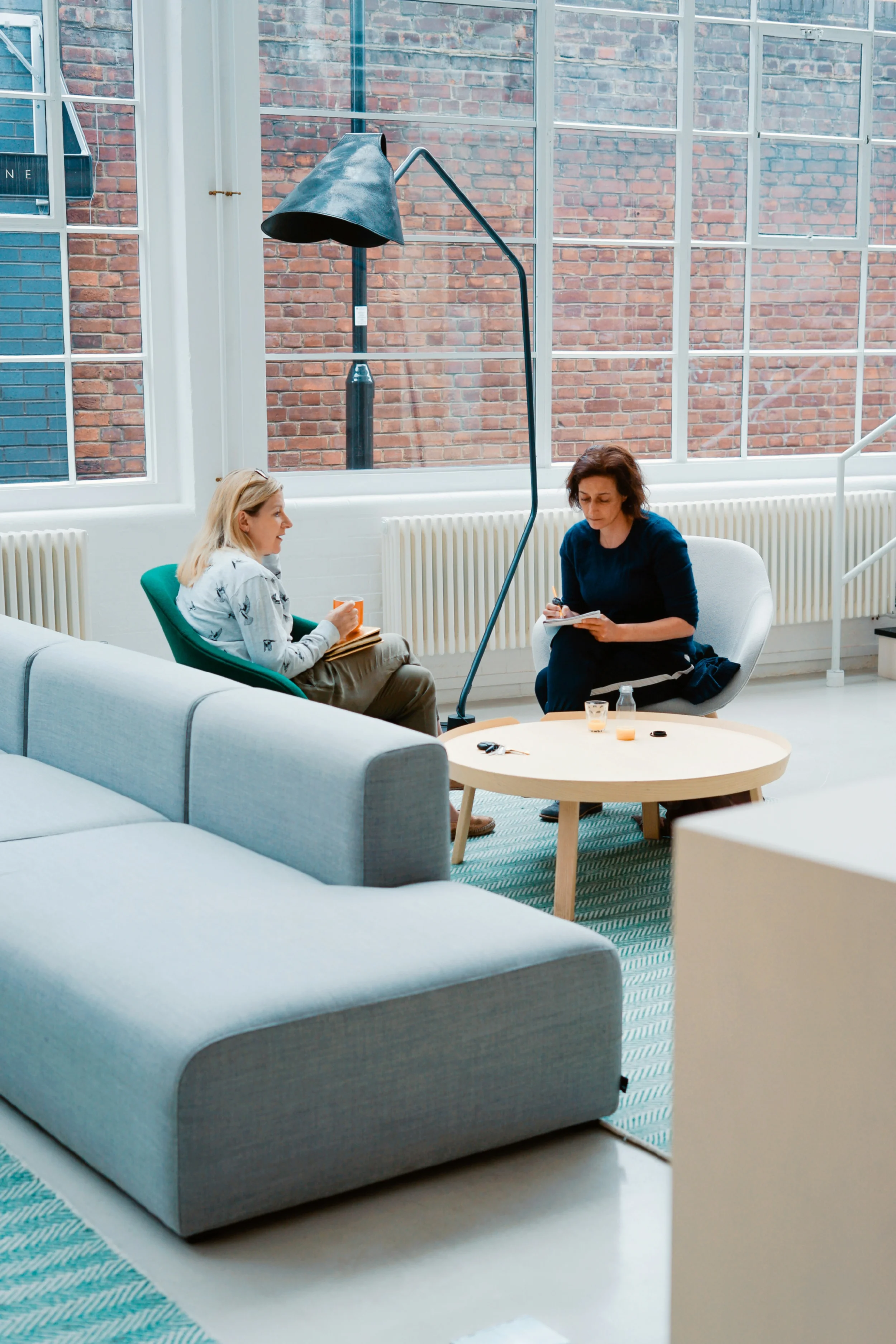 Two women sitting in a modern office setting having a discussion.